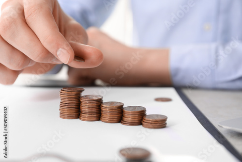 Man stacking coins at table indoors, closeup