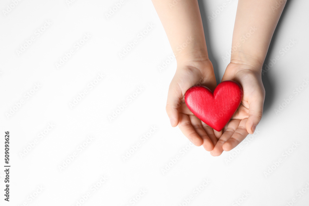 Obraz premium Woman holding red heart in hands on white background, top view
