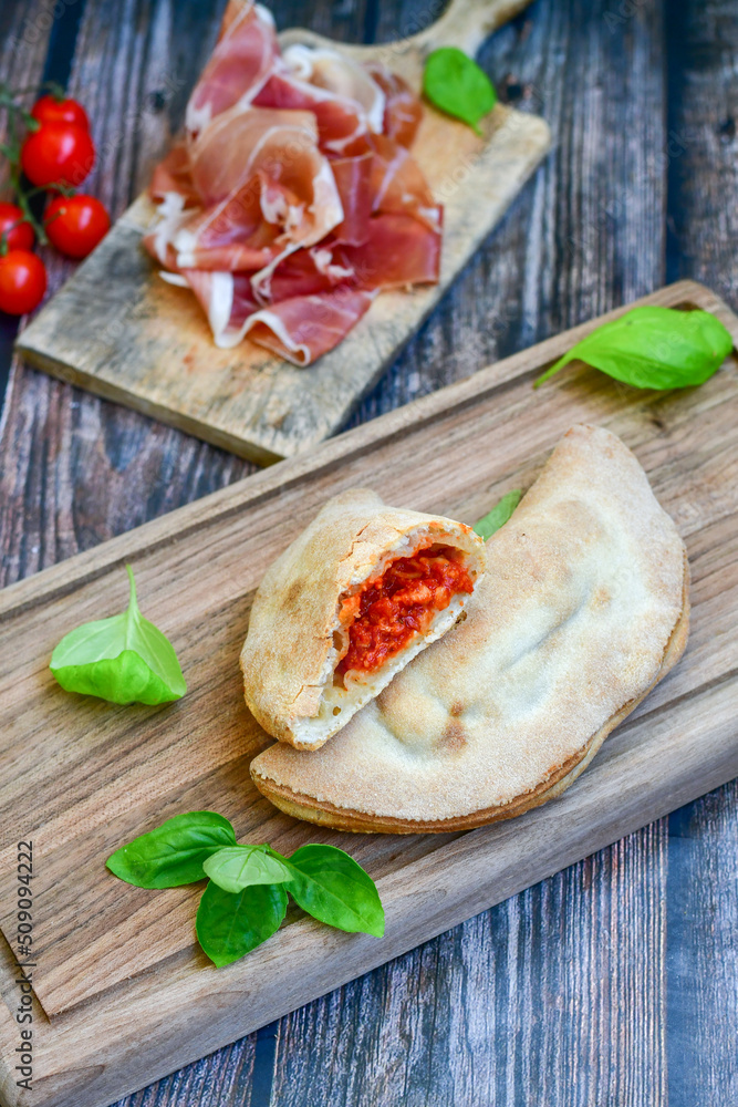 Home made italian calzone pizza with  tomatoes, mozzarella and parmesan cheese and fresh basil 