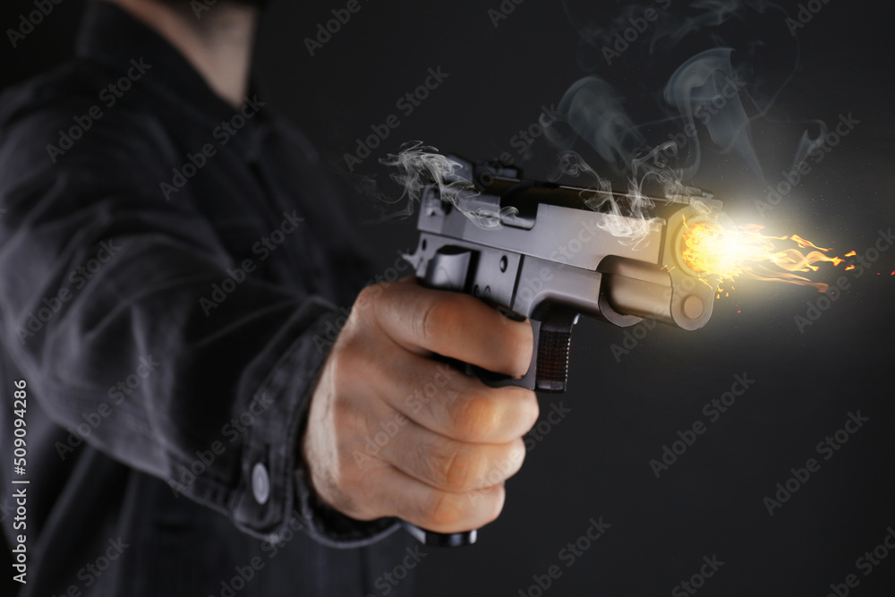 Man shooting handgun on black background, closeup Man shooting handgun on black background, closeup