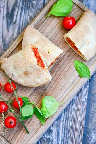 Home made italian calzone vegetarian  pizza with  tomatoes, mozzarella and parmesan cheese and fresh basil 