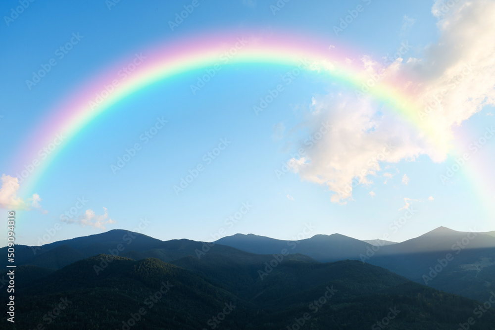 Picturesque mountain landscape and beautiful rainbow in blue sky