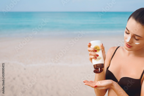 Close up beautiful woman in bikini applying sun cream on hands. Sun protection. Skin care. Girl using sunscreen to skin. Portrait of female holding Suntan lotion and moisturizing sunblock.