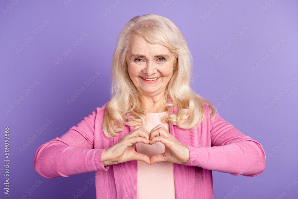 Photo of lovely senior woman show fingers heart symbol romantic cupid dream isolated over purple color background Photo of lovely senior woman show fingers heart symbol romantic cupid dream isolated over purple color background