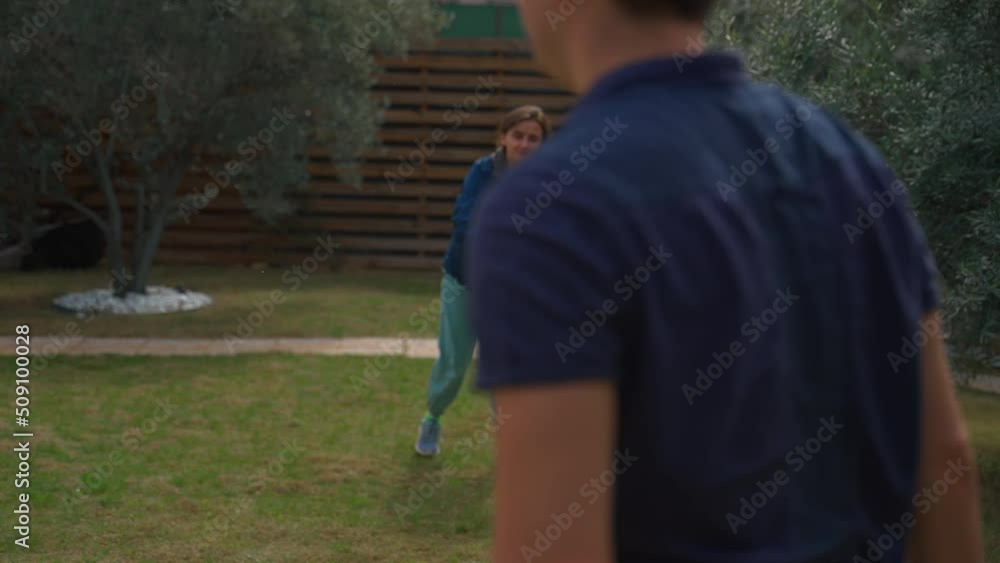 Woman catches green flying frisbee thrown by man against brown fence in countryside. Couple plays fun game in yard on cloudy day slow motion Woman catches green flying frisbee thrown by man against brown fence in countryside. Couple plays fun game in yard on cloudy day slow motion
