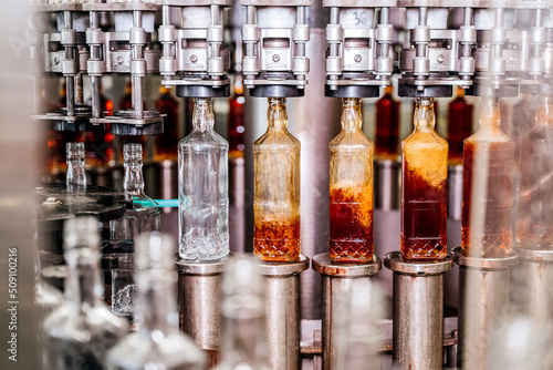 Alcohol beverage factory. Bottles on conveyor belt of bottle filling machine photo