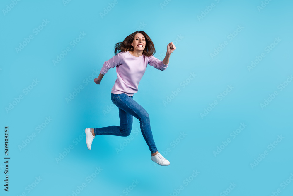 Full body profile side photo of young excited woman runner jumper hurry isolated over blue color background