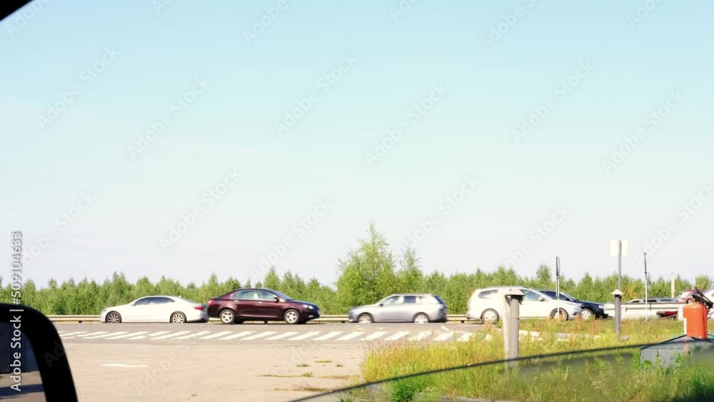 Cars drive slowly along the highway during the day.