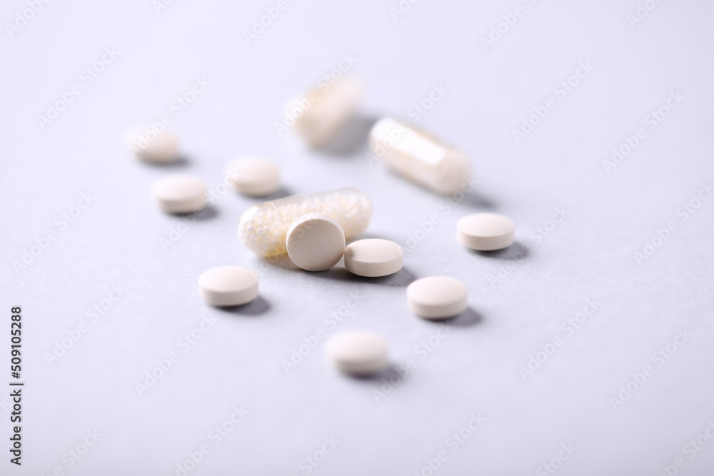 Vitamin C tablets and capsules on bright paper background. Soft focus. Close up. Copy space. Vitamin C tablets and capsules on bright paper background. Soft focus. Close up. Copy space.