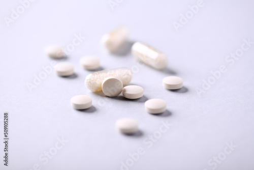 Vitamin C tablets and capsules on bright paper background. Soft focus. Close up. Copy space. 