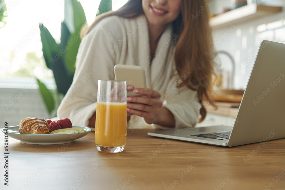 Close-up of beautiful woman in bathrobe using technologies while spending time at the kitchen Close-up of beautiful woman in bathrobe using technologies while spending time at the kitchen