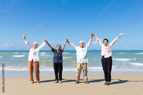 portrait group of seniors man and women with arms raised on the beach