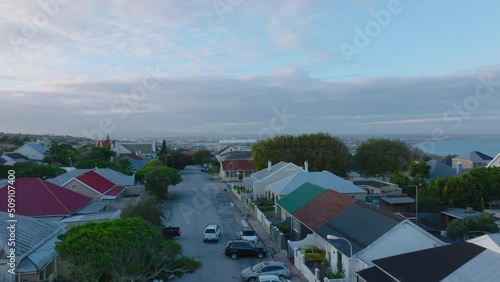 Residential houses with colour roofs along street in city. Forwards fly above urban neighbourhood, revealing panoramic view of town. Port Elisabeth, South Africa