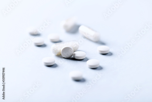 Vitamin C tablets and capsules on bright paper background. Soft focus. Close up. Copy space.