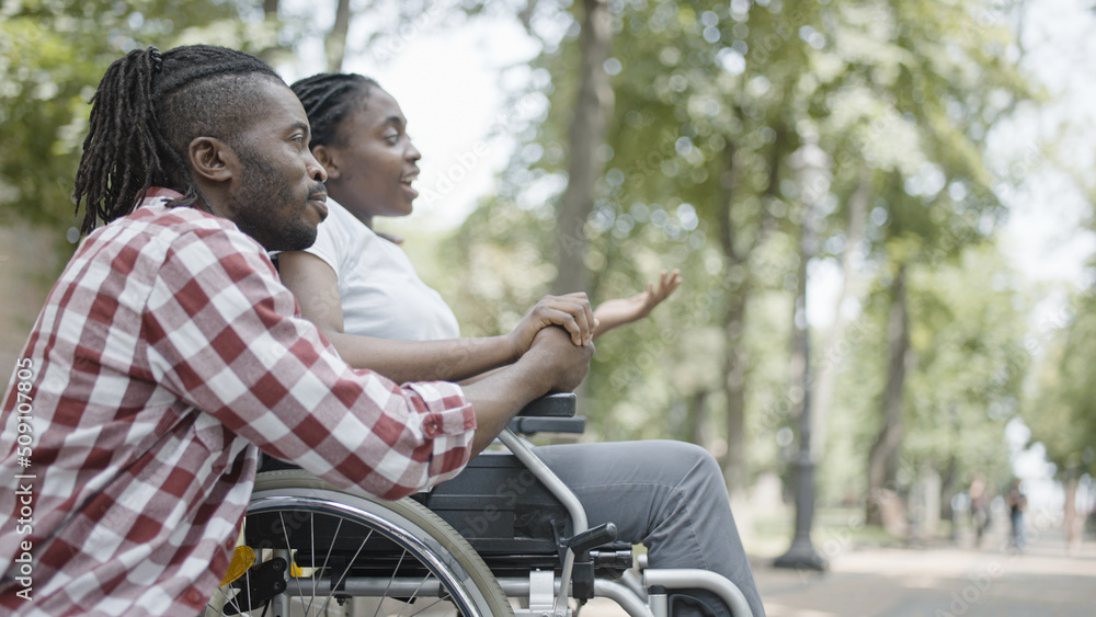 Happy man and woman in wheelchair having fun together in park, relationship Happy man and woman in wheelchair having fun together in park, relationship