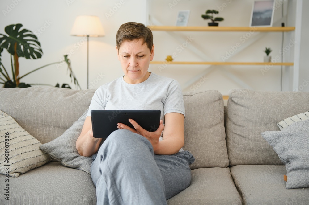 people, technology and internet concept - happy middle aged woman with tablet pc computer at home.