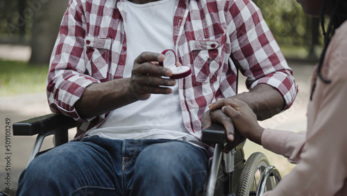 Close-up of African American man with disability presenting engagement ring to his girlfriend