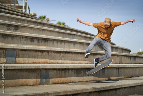 A young man doing an ollie 360 flip with his skateboard on some bleachers photo