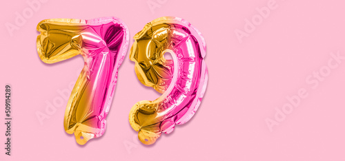 Rainbow foil balloon number, digit seventy nine on a pink background. Birthday greeting card with inscription 79. Top view. Numerical digit. Celebration event, template. Banner