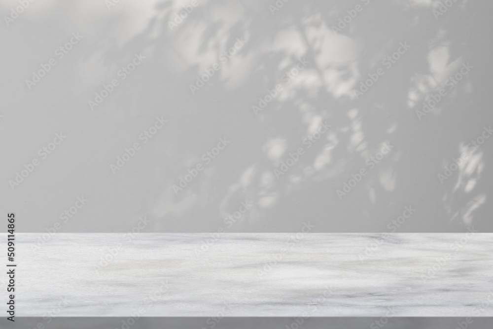 Fototapeta premium Marble table with tree shadow drop on white wall background for mockup product display