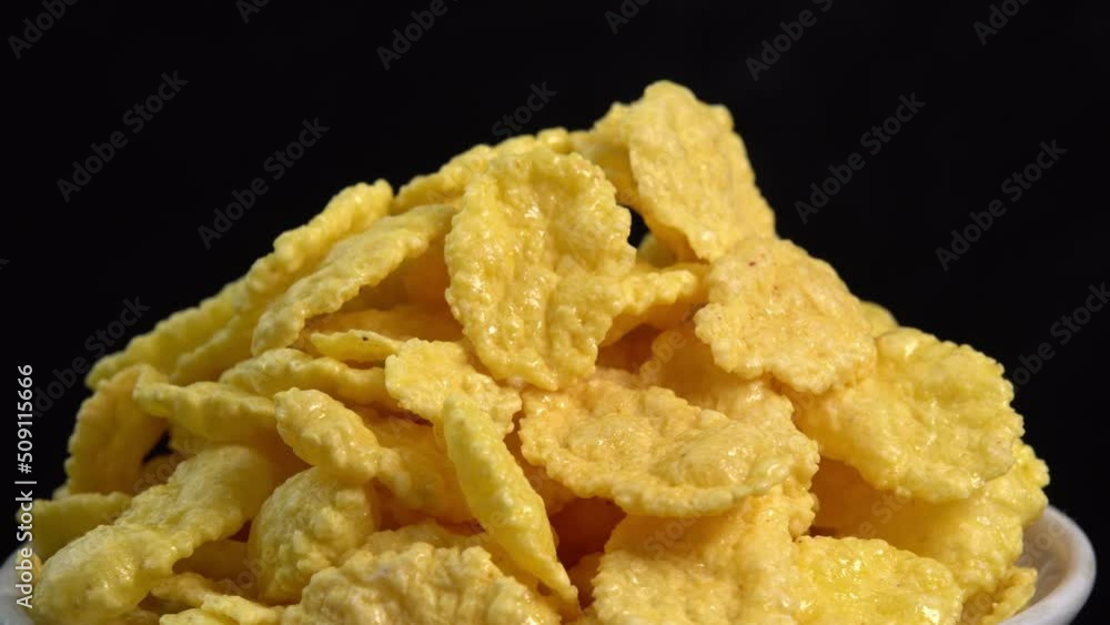 Crispy corn flakes rotating in bowl on black background close up, dry healthy breakfast. Honey cornflakes for healthy cereal breakfast. Cooking healthy breakfast concept. High quality 4k footage Crispy corn flakes rotating in bowl on black background close up, dry healthy breakfast. Honey cornflakes for healthy cereal breakfast. Cooking healthy breakfast concept. High quality 4k footage