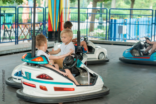 Young drivers competing on mini car racing. Boys driving bumper cars in an amusement park.