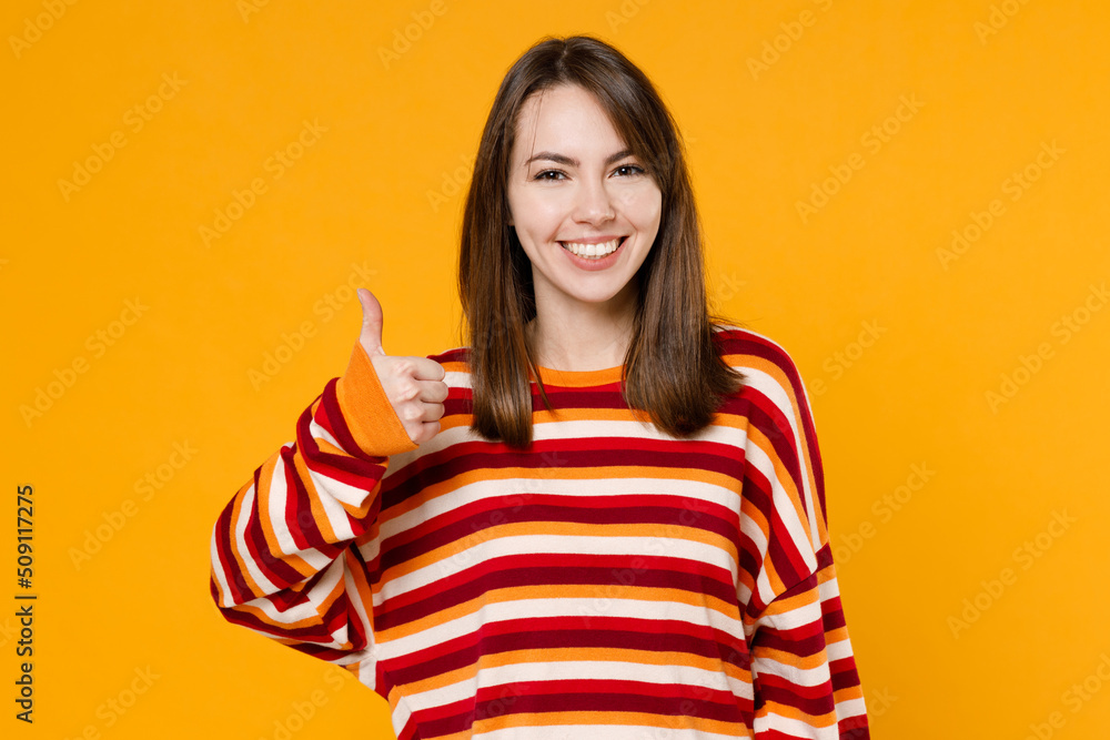 Young happy smiling satisfied cheerful fun cool caucasian woman 20s in red striped sweatshirt show thumb up like gesture isolated on plain yellow background studio portrait. People lifestyle concept. Young happy smiling satisfied cheerful fun cool caucasian woman 20s in red striped sweatshirt show thumb up like gesture isolated on plain yellow background studio portrait. People lifestyle concept.