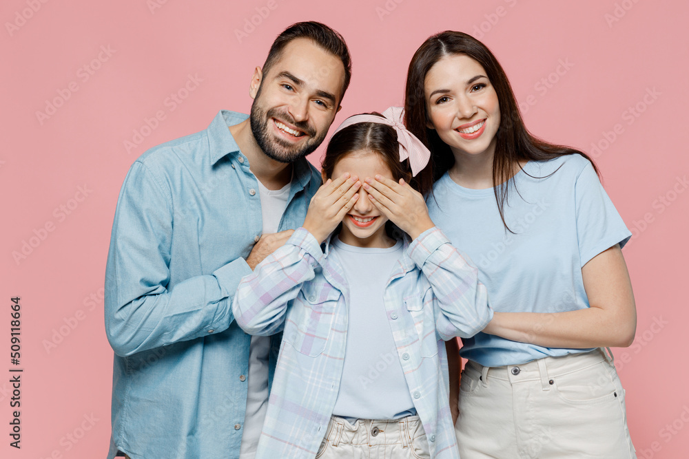 Young parents mom dad with child kid daughter teen girl in blue clothes close eyes with hands play guess who or hide and seek hug isolated on plain pastel light pink background. Family day concept Young parents mom dad with child kid daughter teen girl in blue clothes close eyes with hands play guess who or hide and seek hug isolated on plain pastel light pink background. Family day concept