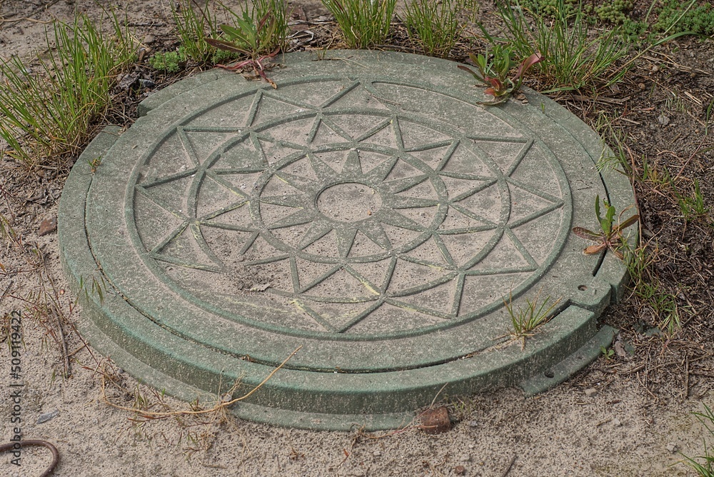 one old green iron sewer manhole on gray asphalt road in grass