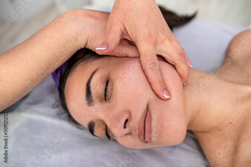 female beautician doing facial massage her female client in a beauty clinic