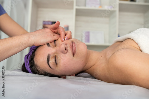 pretty woman getting enjoying facial massage with closed eyes at beauty salon