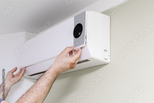 a man removes the cover of the air conditioner for repairs. hands close up