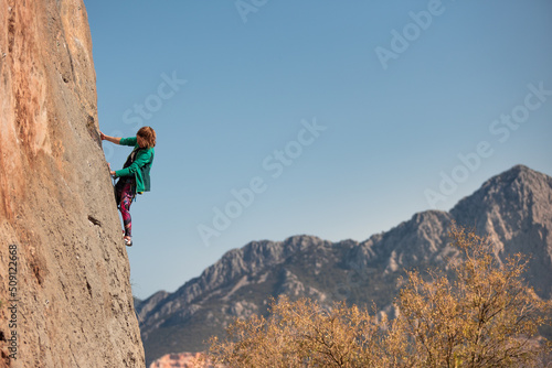 A woman climbs a rock