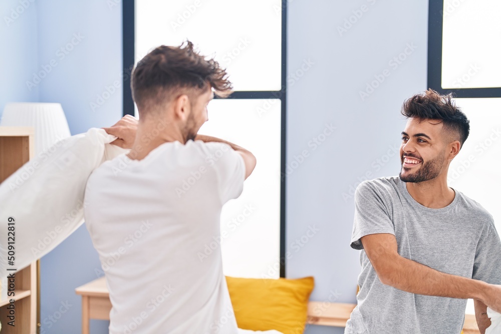 Fototapeta premium Young couple fighting with pillow on bed at bedrooom