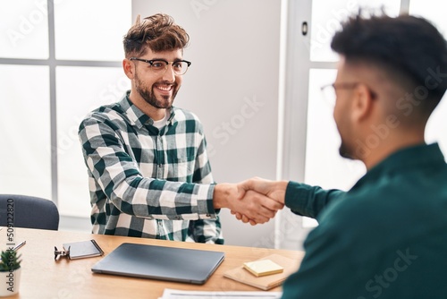 Young couple business workers shake hands at office