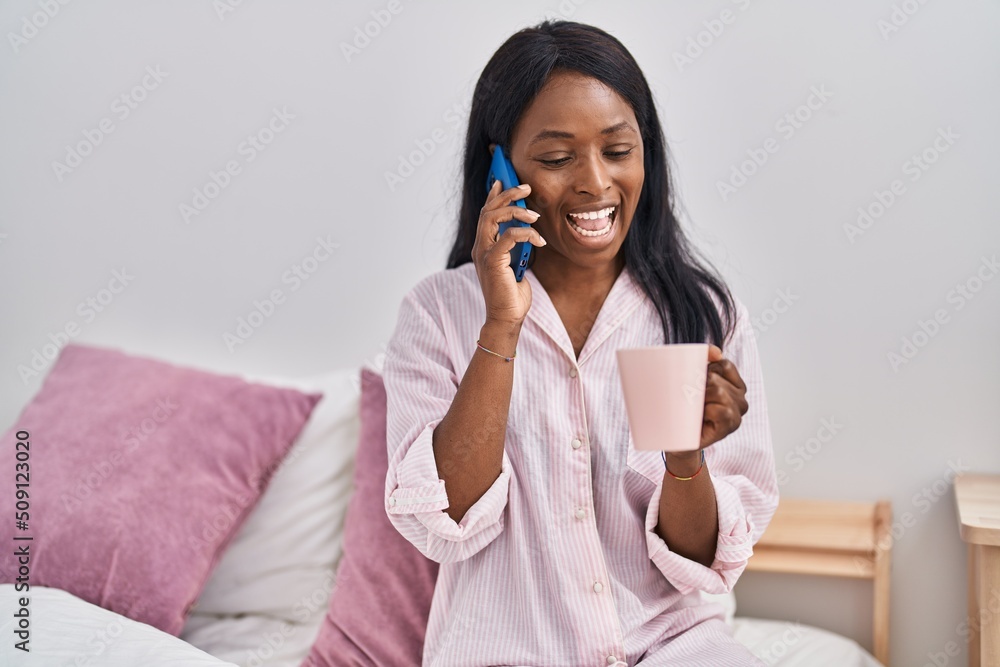 Young african american woman drinking coffee talking on the smartphone at bedroom Young african american woman drinking coffee talking on the smartphone at bedroom