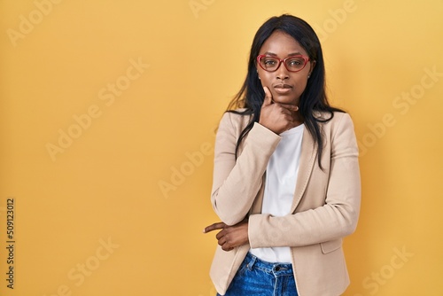 African young woman wearing glasses looking confident at the camera with smile with crossed arms and hand raised on chin. thinking positive. © Krakenimages.com