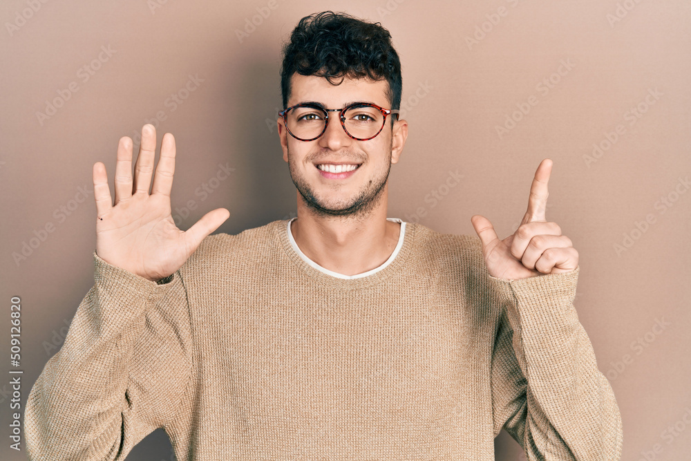 Young hispanic man wearing casual clothes and glasses showing and pointing up with fingers number seven while smiling confident and happy. Young hispanic man wearing casual clothes and glasses showing and pointing up with fingers number seven while smiling confident and happy.