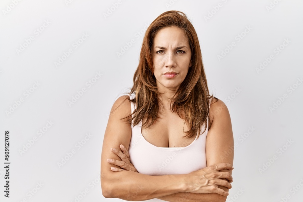 Middle age hispanic woman standing over isolated background skeptic and nervous, disapproving expression on face with crossed arms. negative person. Middle age hispanic woman standing over isolated background skeptic and nervous, disapproving expression on face with crossed arms. negative person.