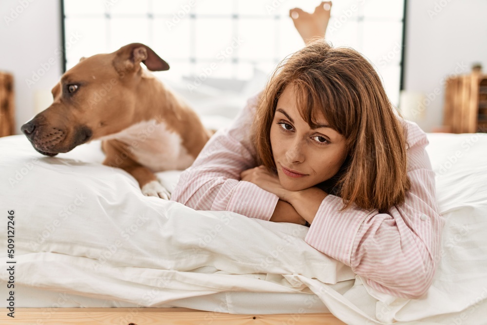 Young caucasian woman lying on bed with dog at bedroom Young caucasian woman lying on bed with dog at bedroom