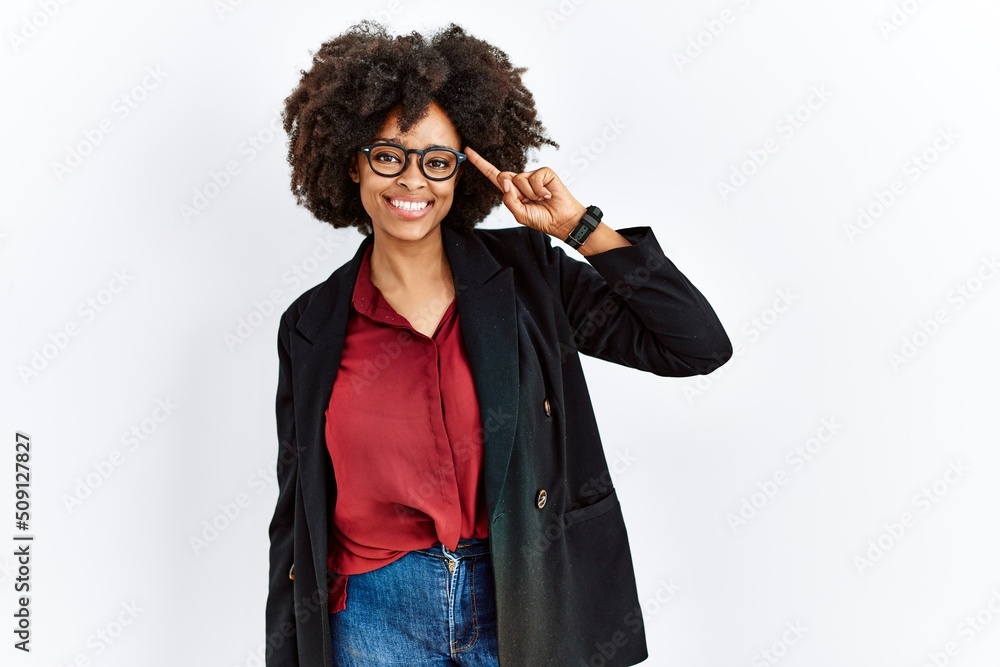 African american woman with afro hair wearing business jacket and glasses smiling pointing to head with one finger, great idea or thought, good memory African american woman with afro hair wearing business jacket and glasses smiling pointing to head with one finger, great idea or thought, good memory