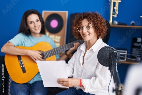 Two women musicians having classical guitar lesson at music studio