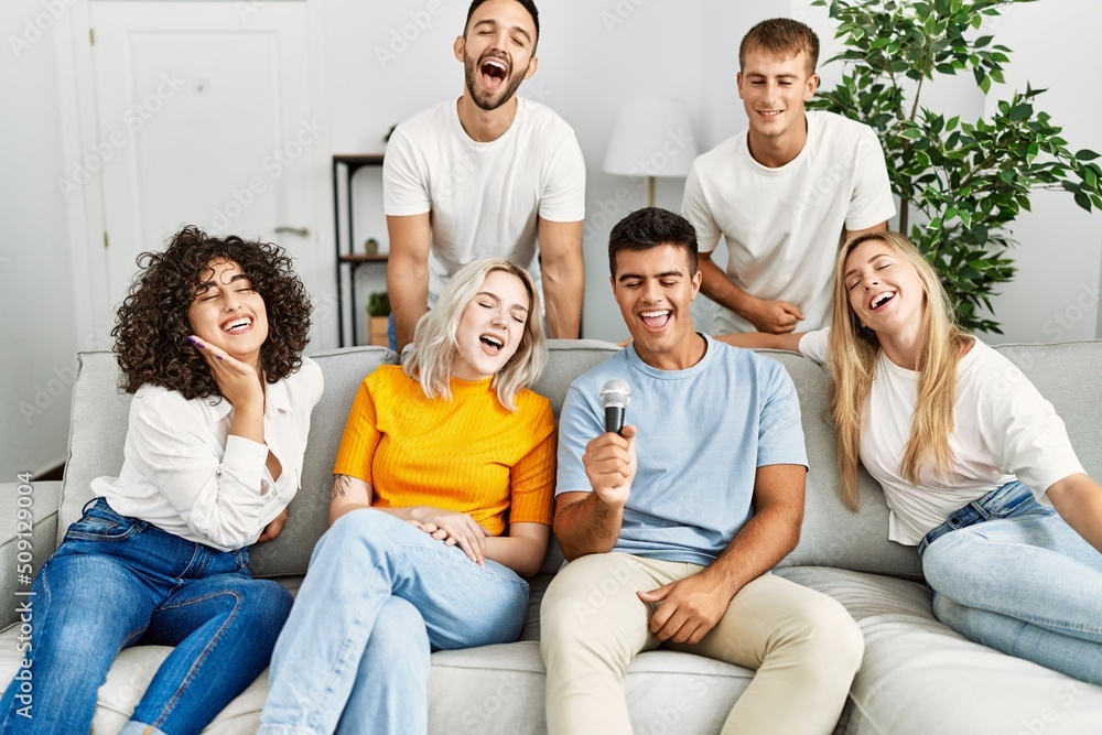 Group of young friends having party singing song using microphone at home. Group of young friends having party singing song using microphone at home.