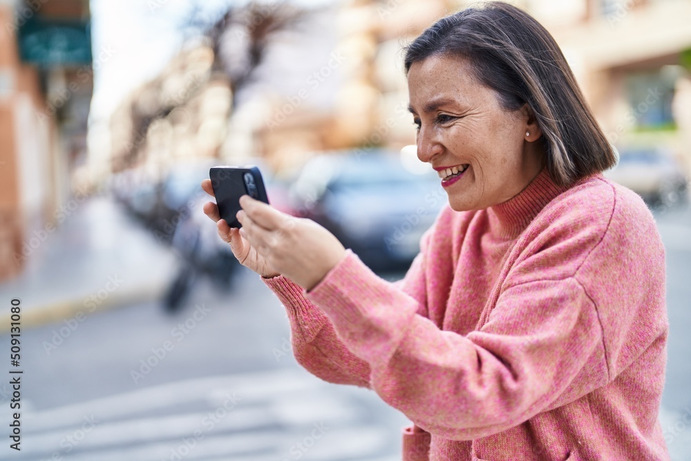 Middle age woman smiling confident watching video on smartphone at street Middle age woman smiling confident watching video on smartphone at street
