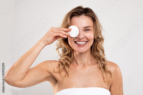 Facial Skincare. Cheerful Middle Aged Lady Covering Eye With Cotton Pad