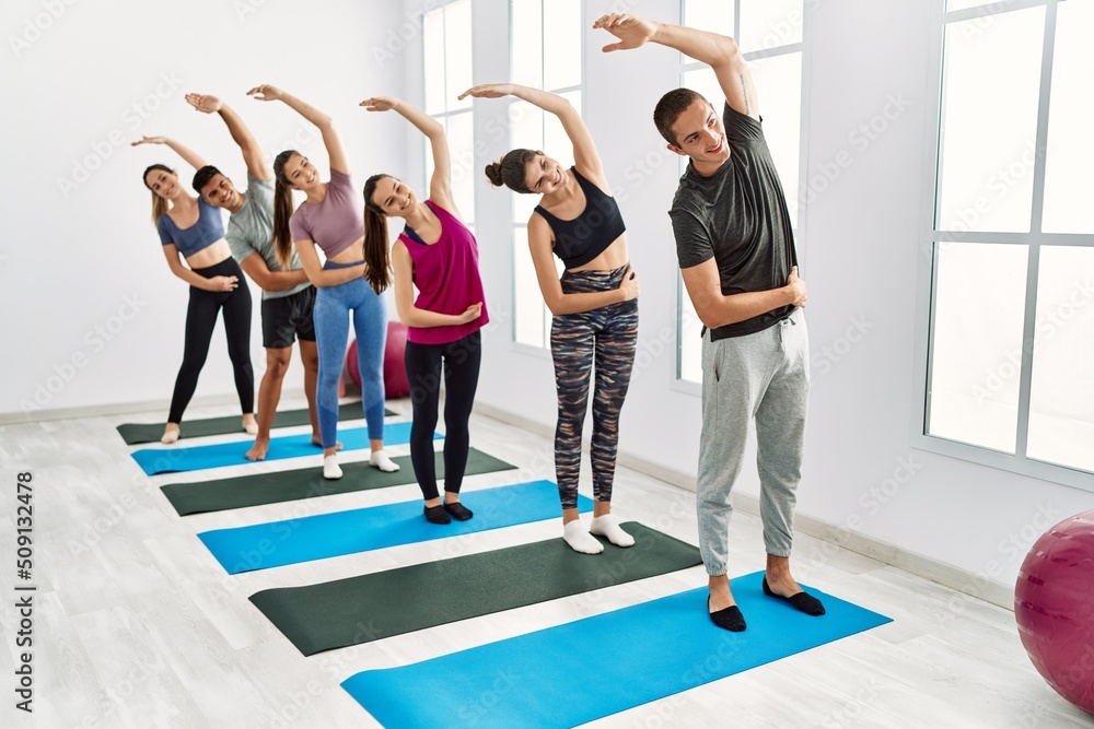 Fototapeta premium Group of young hispanic people smiling happy stretching at sport center.