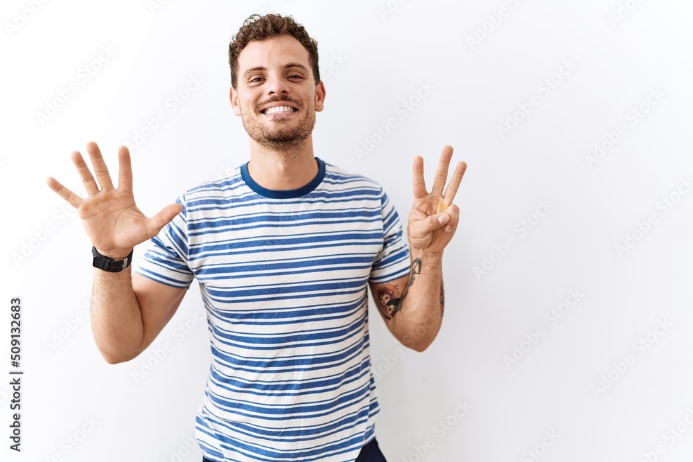 Handsome young man standing over isolated background showing and pointing up with fingers number eight while smiling confident and happy. Handsome young man standing over isolated background showing and pointing up with fingers number eight while smiling confident and happy.