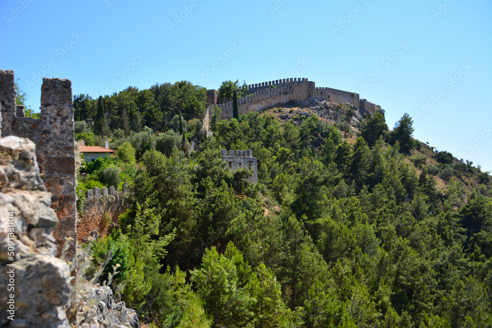 ancient brick medieval wall on top of mountain among pine trees in sunny day