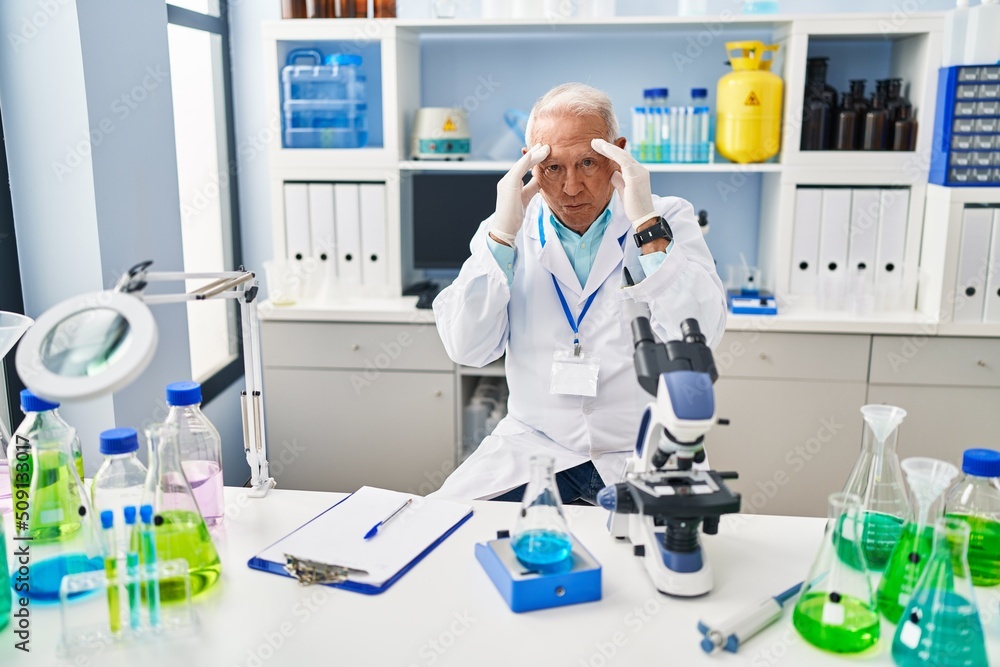 Senior man wearing scientist uniform measuring liquid at laboratory Senior man wearing scientist uniform measuring liquid at laboratory