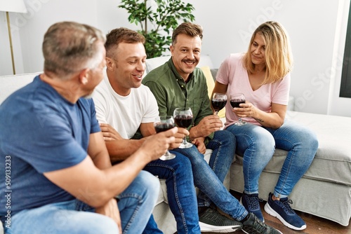 Group of middle age friends toasting with glass of wine at home.